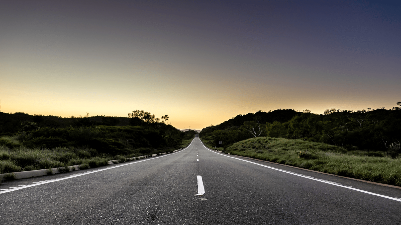 A long straight road with a beautiful sunset behind it